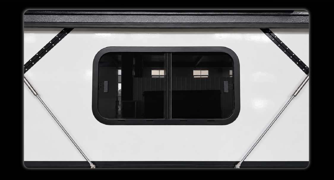 Close-up of black tinted sliding window on white camper showing black frame and privacy glass