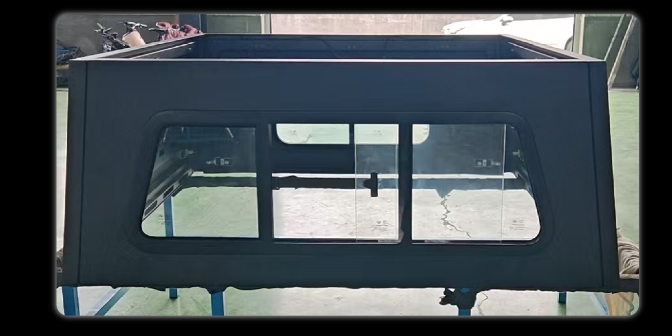 Large front window installed on black camper shell exterior showing sliding glass panels