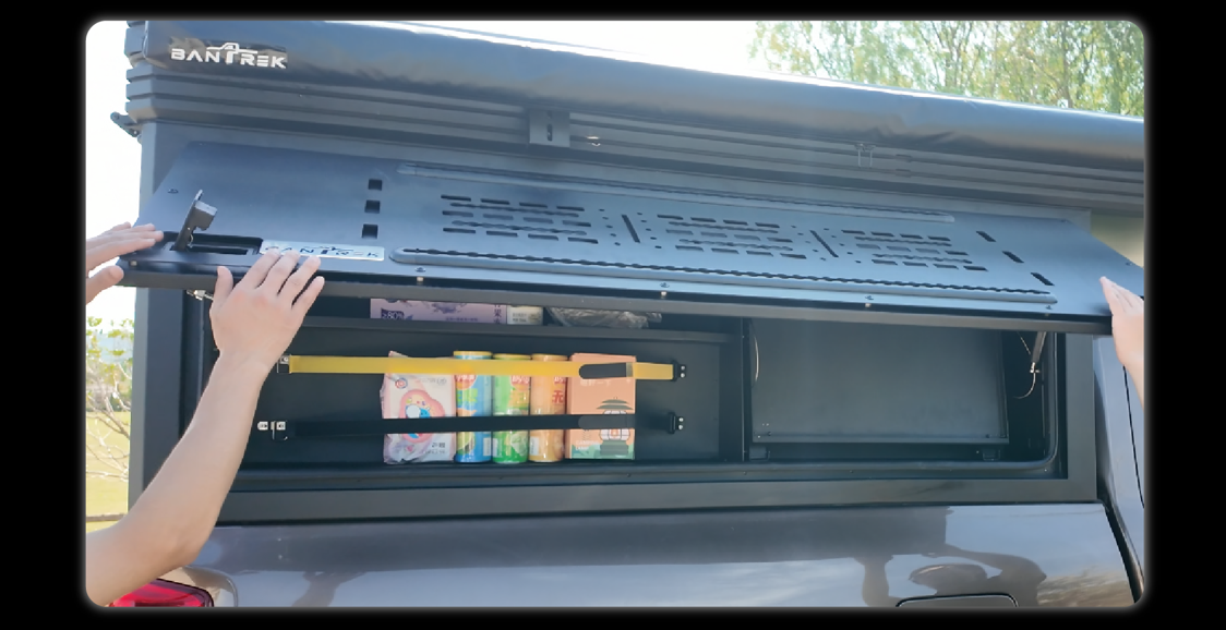 Hands opening slide-out kitchen door showing MOLLE panel interior and secured drinks storage